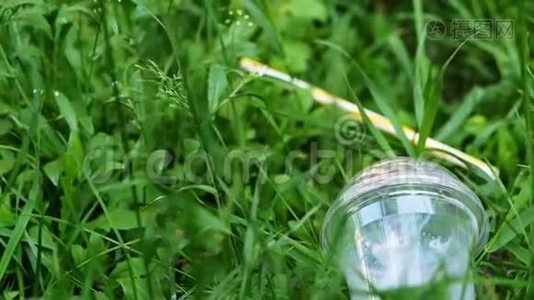 塑料杯躺在森林里的草地上，污染视频