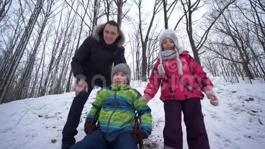 在冬天的周末，孩子们和爸爸一起玩，在雪地森林里跑步和滑雪视频