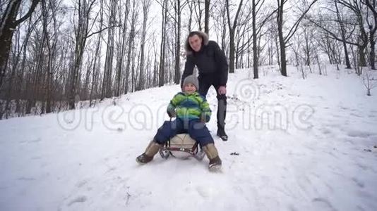 父子俩坐在雪山上的雪橇上，在森林里休息视频