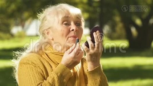 老年妇女涂口红，向朋友吹嘘抗衰老的化妆品视频