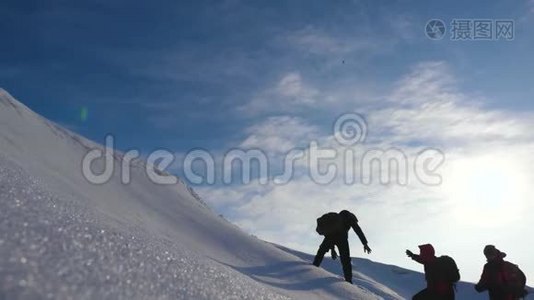 登山者双手互相帮助爬上一座下雪的小山。 冬季旅游中协调良好的团队合作。 小组成员视频