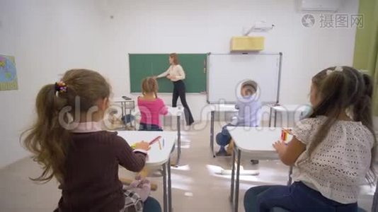 孩子们上学，小老师女靠近黑板，在教室的课桌上给孩子们上认知课视频