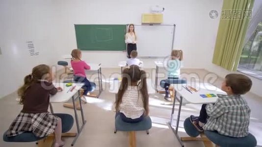 一群小学生在上课时举手回答问题，坐在教师面前的课桌前上小学视频
