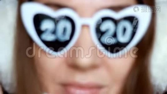 戴墨镜的女人，号码是2020。 新年。 圣诞节。 女孩微笑着看着相机。 选择性重点视频