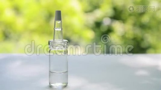 一个装有乳清的吸管的玻璃瓶立在白色的桌子上，背景是随风摇曳的树木视频