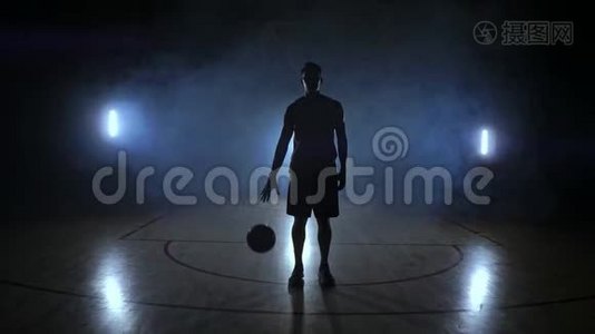 篮球运动员站在黑暗的操场上，手里拿着球，在黑暗中看着镜头视频