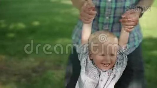一个小男孩在公园里和他爸爸玩耍时的肖像。 爸爸摆动他的小男孩慢速高清视频