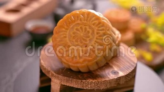 美丽的月饼在木制托盘上旋转，黑色石板背景上有茶和花。 中国传统中秋节视频