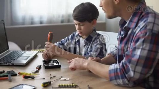 关爱的父亲教他的小儿子在家修理硬盘驱动器，爱好视频