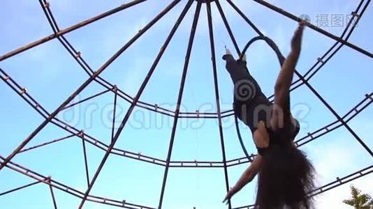 一个可爱的黑发女人倒挂在空中的戒指上，慢慢地转动视频