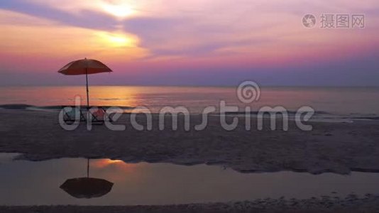 清晨的日出在海中反射，海滩上有椅子和雨伞。视频