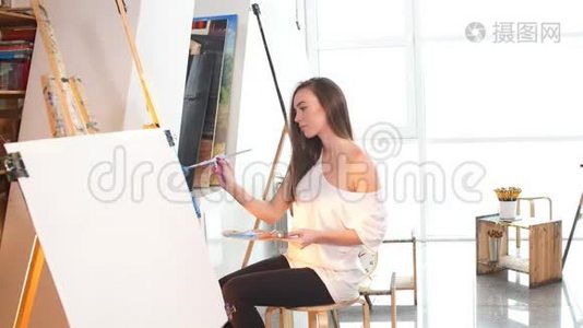 一位女艺术家在车间里用油画颜料在画布上作画。视频