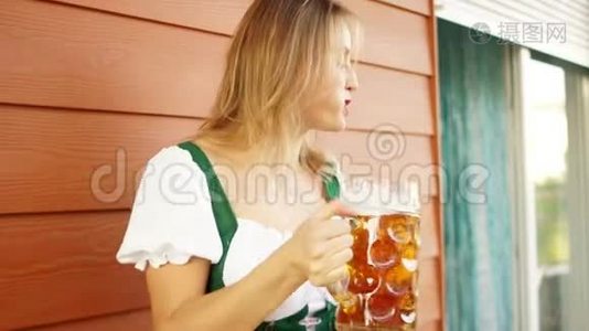 一个穿着巴伐利亚民族服装的女孩模特手里拿着一杯啤酒和一块椒盐脆饼，她生气地咒骂着。 红色视频