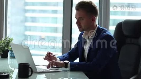 年轻英俊的商人在他办公室的电脑上工作。视频
