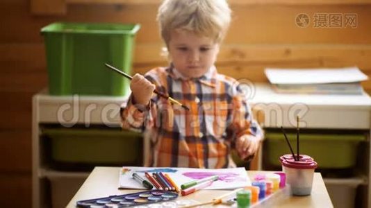 学龄前男孩在日托中心用五颜六色的颜料玩。 创意孩子幼儿在家画画.. 儿童玩耍视频