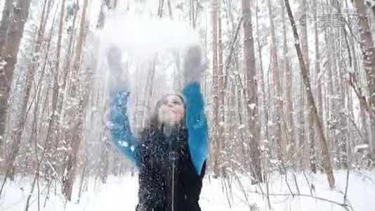 在冬天的森林里，一个年轻的女人微笑着把雪抛起视频