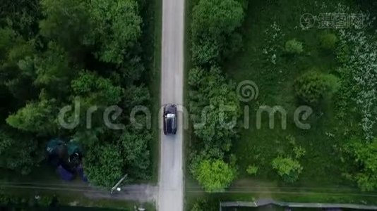 村里的路。 汽车沿着树和房子之间的道路行驶。视频