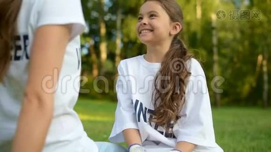 坐在草地上和志愿者交谈的活泼的女孩视频
