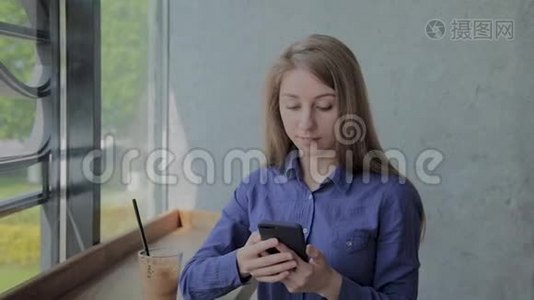漂亮的女孩坐在窗边，在咖啡馆里拿着电话。视频
