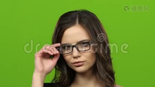 戴眼镜的女孩开始调情，并从性上摘下眼镜。 绿色屏幕。 关门视频