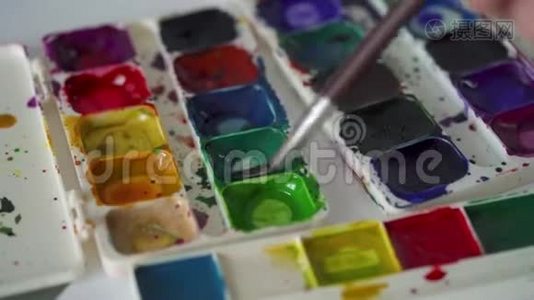 画笔从调色板中提取不同颜色的水彩颜料并将其混合视频