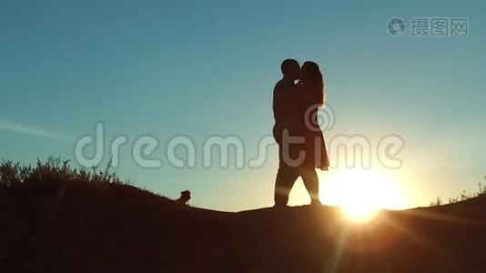 情侣在夕阳下剪影亲吻拥抱.. 慢动作录像。 年轻夫妇在日落时接吻。 每个男人和女孩见面视频