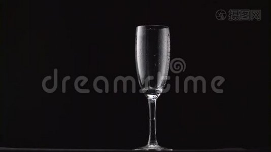 香槟被倒入薄柄上的薄雾玻璃中。 黑色背景视频