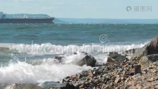 海浪拍打着海岸上的岩石，背景上的货船视频