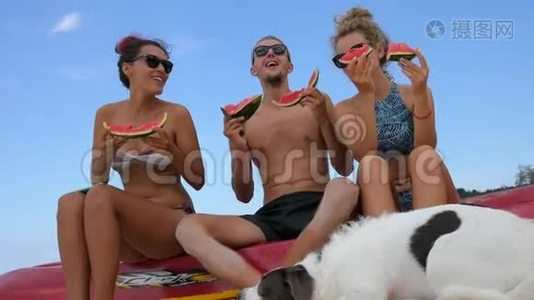 年轻的无忧无虑的朋友在海滩上享受乐趣和吃西瓜。 泰国Koh Phangan。视频