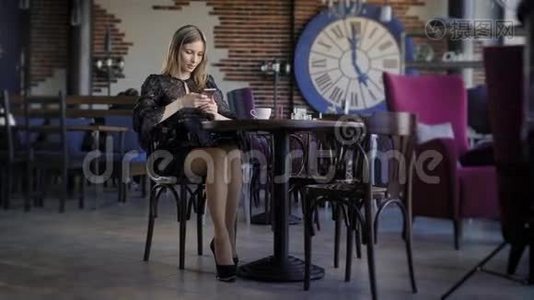 年轻可爱的女人用电话，坐在咖啡馆里拿着智能手机，接短信。 一位漂亮的商界女性视频