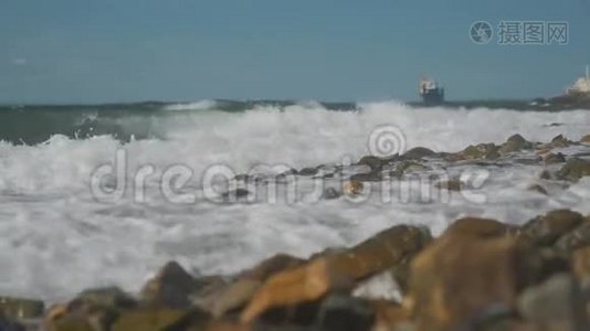 海浪拍打着海岸上的岩石，背景上的货船视频