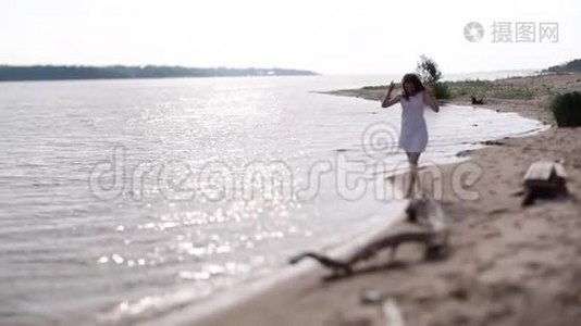一个穿着白色连衣裙的女孩沿着水边奔跑。视频