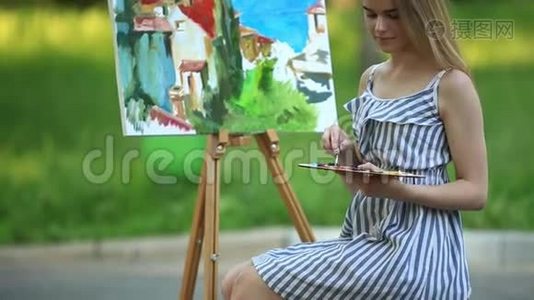 美丽的女孩艺术家坐在公园的凳子上，拿着颜料调色板视频
