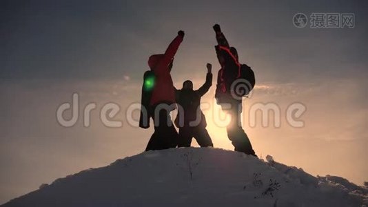 游客们来到雪山顶上，在黄色日落的背景下为胜利而欢欣鼓舞。 游客的团队合作和视频