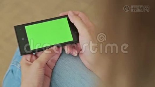 漂亮的女人拿着绿色屏幕显示和滚动的智能手机视频
