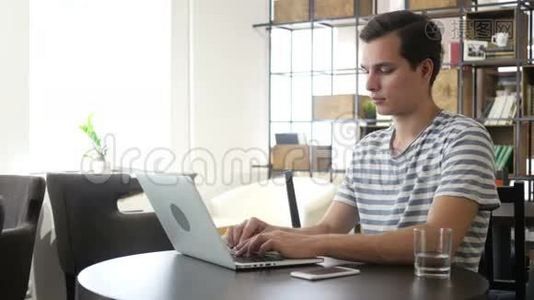 有笔记本电脑的年轻人在工作场所工作，打字，思考视频