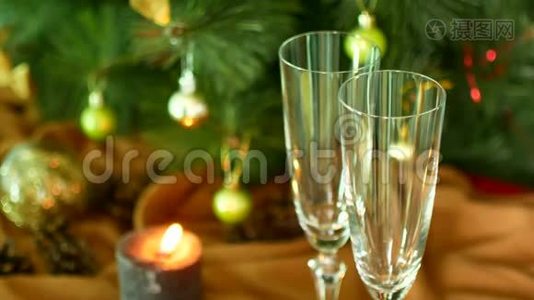 平安夜。 把香槟倒在玻璃杯上。 背景上的圣诞树和蜡烛。视频