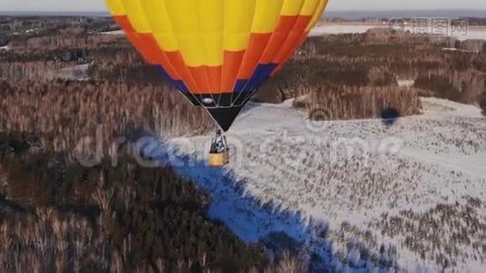 空中拍摄的人们乘坐一个大明亮的气球飞越冬季森林。视频