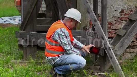 建筑工人检查木脚手架，并在平板电脑上拍照视频