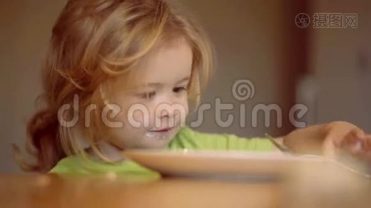 小男孩坐在桌子旁吃牛奶零食。 孩子吃东西。 孩子在家吃健康的食物。 年幼的孩子视频