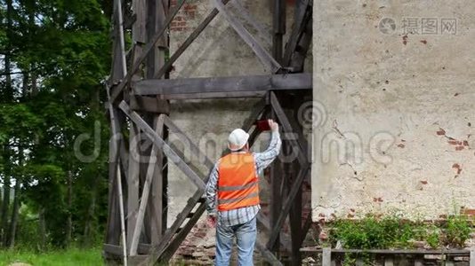 建筑工人在木脚手架附近的智能手机上行走和拍照视频