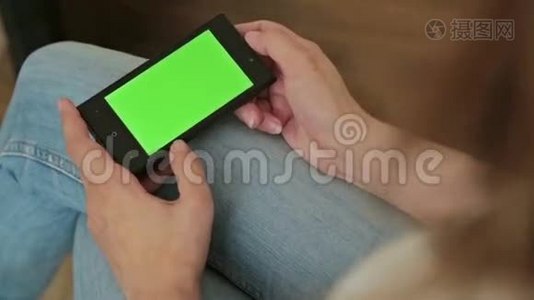 漂亮的女人手里拿着绿色屏幕显示的智能手机视频