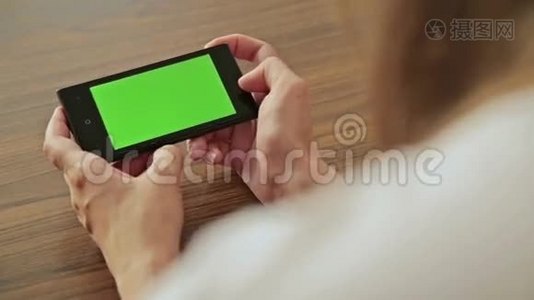 漂亮的女人手里拿着绿色屏幕显示的智能手机视频
