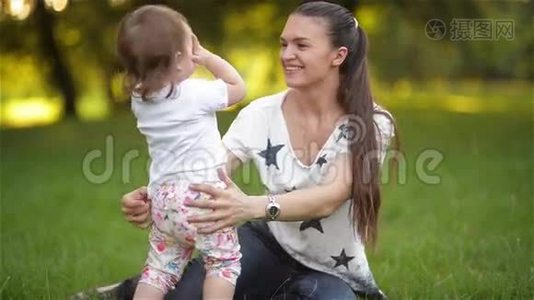 母女俩相爱相拥在公园玩耍，小妈妈在花园里和孩子玩耍，家庭幸福视频