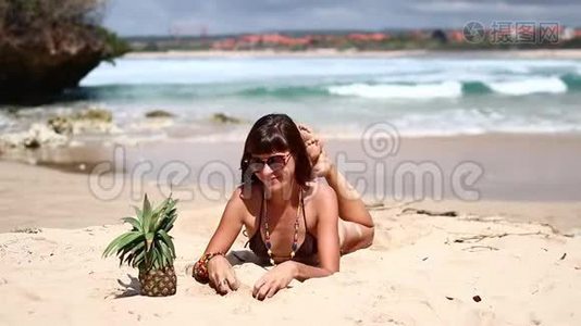 穿着棕色泳衣的女人和菠萝在海滩上。 在热带巴厘岛享受暑假的年轻女性视频