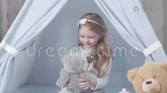 小可爱的金发女孩坐在玩具屋里玩玩具视频