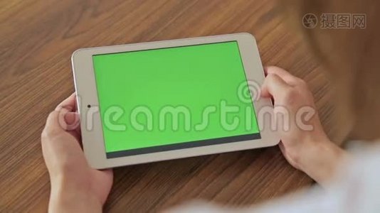 漂亮的女人手拿着绿色屏幕显示器的平板电脑视频