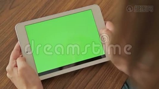 漂亮的女人手拿着绿色屏幕显示器的平板电脑视频
