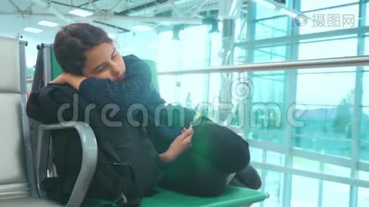 疲惫的少女少年旅行者睡在机场，等待飞机起飞，登机口的长椅上，她的行李都在她身边视频