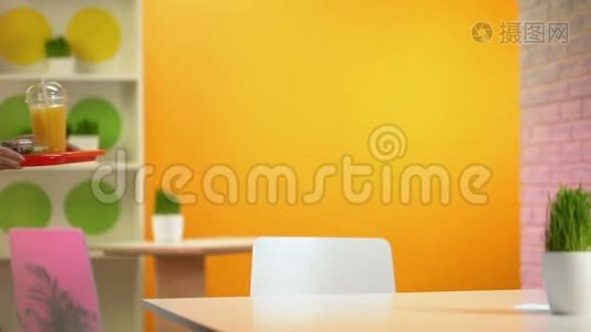 快乐的女人把托盘和沙拉和新鲜橙汁放在桌子上，小吃店视频